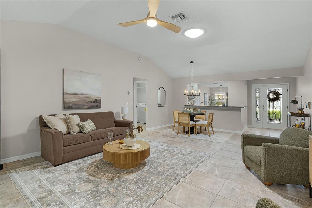 A living room with a brown sofa, round coffee table, dining area, and tiled floors — 634 ALLENWOOD LOOP, THE VILLAGES, FL