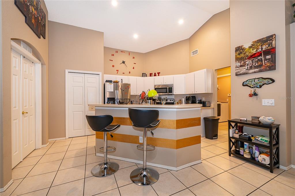 A kitchen features a breakfast bar with two stools, white cabinetry, and tiled flooring — 1152 VIEW POINTE CIRCLE, LAKE WALES, FL
