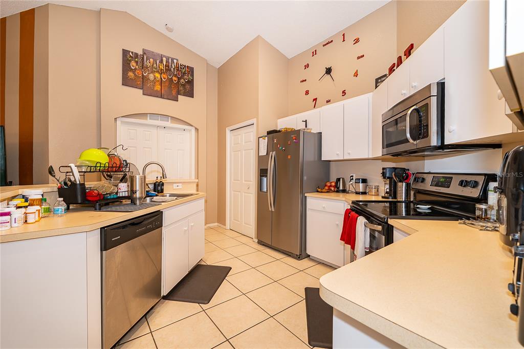 A kitchen with white cabinets, stainless steel appliances, and a wall-mounted clock — 1152 VIEW POINTE CIRCLE, LAKE WALES, FL