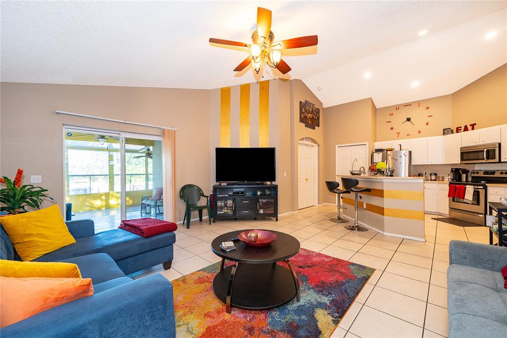 A living room with a blue sectional, colorful rug, and an open kitchen with bar seating — 1152 VIEW POINTE CIRCLE, LAKE WALES, FL