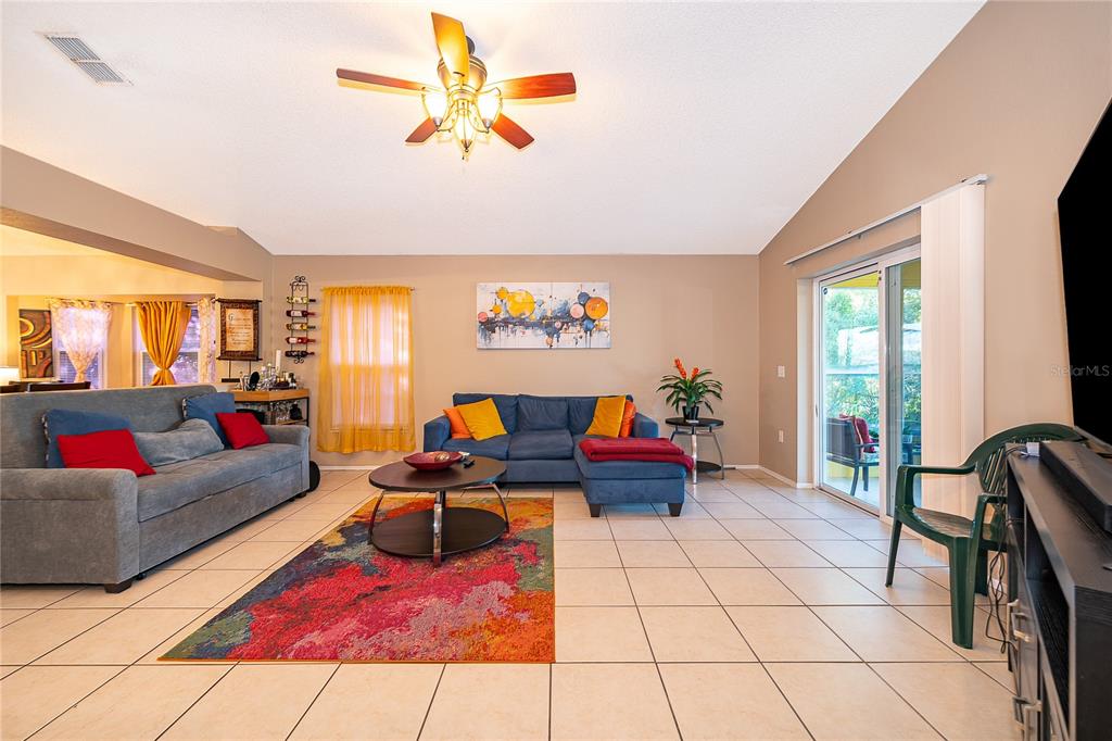 A living room features a blue sectional, a gray sofa, tile flooring, and a ceiling fan — 1152 VIEW POINTE CIRCLE, LAKE WALES, FL