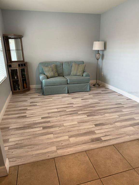 A light blue room features a small sofa, a corner curio cabinet, and wood-look flooring — 412 NOVA DRIVE, DAVENPORT, FL