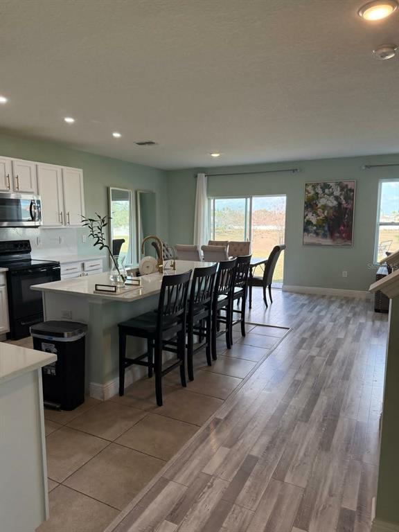 A kitchen with a white island, black bar stools, and light wood-look flooring — 412 NOVA DRIVE, DAVENPORT, FL