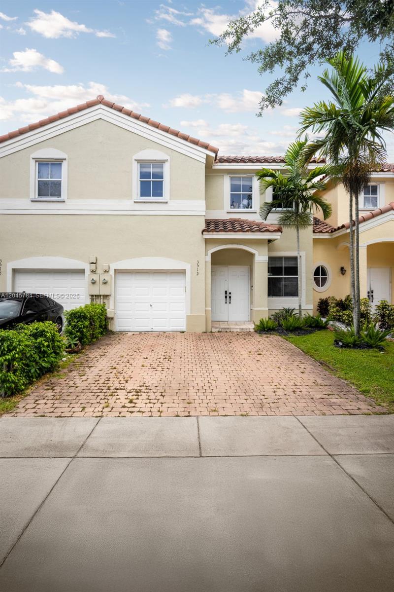 A two-story beige house features a brick driveway, a double garage, and palm trees — 3512 SW 171st Ave, Miramar FL 33027, MIRAMAR, FL