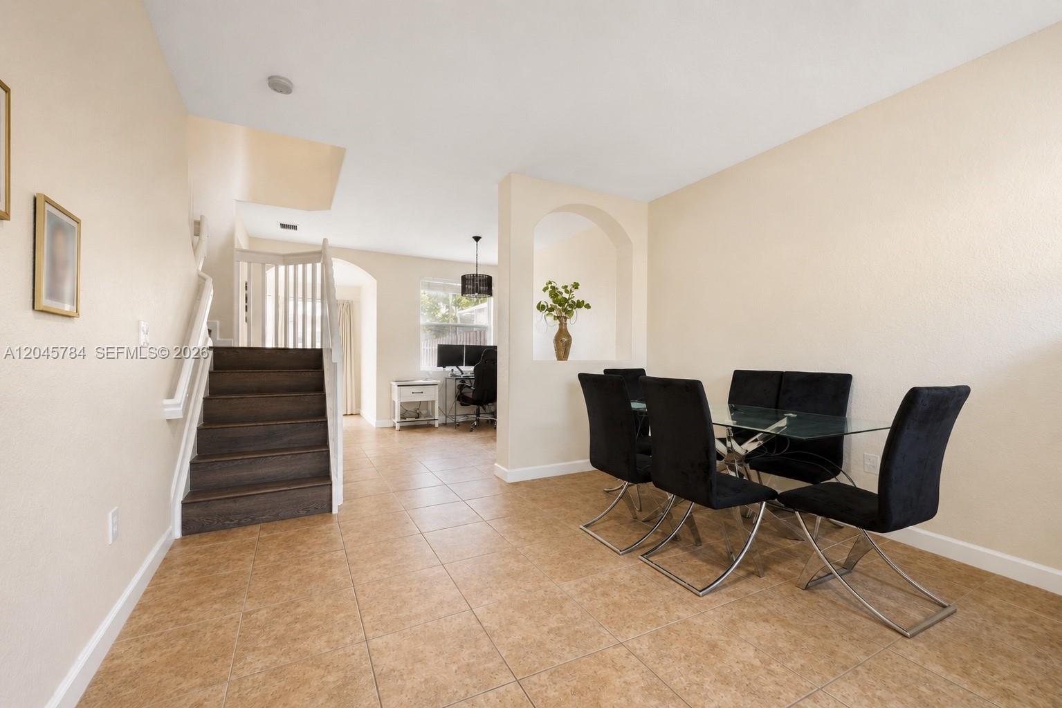A dining area with a glass table and black chairs sits beside a staircase — 3512 SW 171st Ave, Miramar FL 33027, MIRAMAR, FL