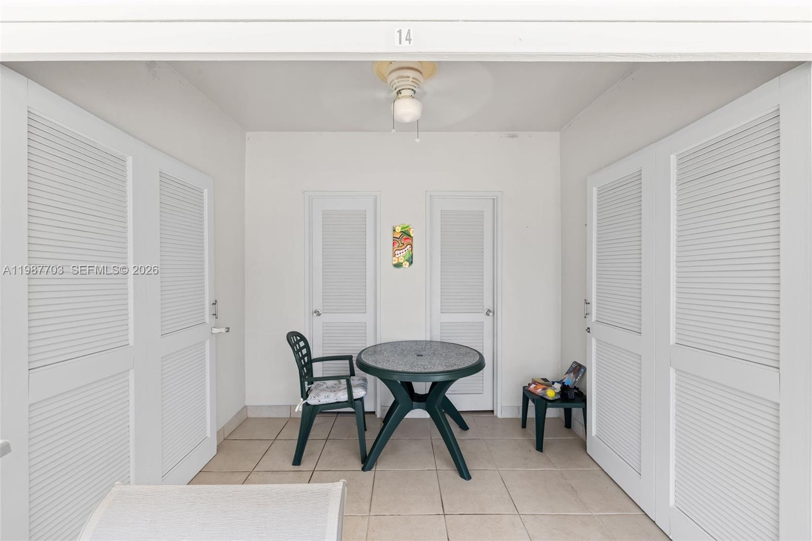 A tiled patio features a round table, one chair, and two louvered doors — 5055 Collins Ave, Miami Beach FL 33140, MIAMI BEACH, FL