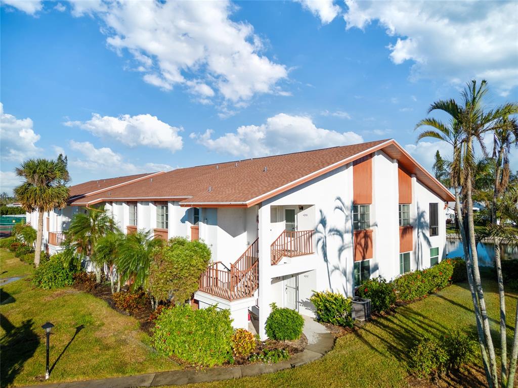 An exterior view of a two-story apartment building with white walls and brown trim — 4859 INDEPENDENCE DRIVE, BRADENTON, FL
