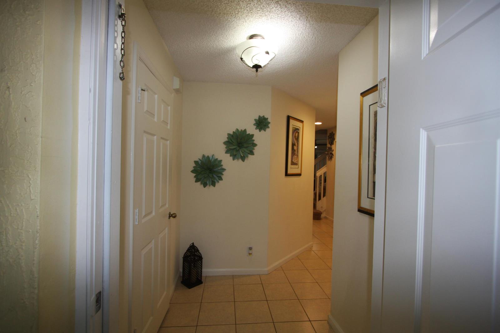 A tiled entryway leads into a hallway featuring wall decor, a lantern, and ceiling lighting — 945 Imperial Lake Road, FL 33413, FL