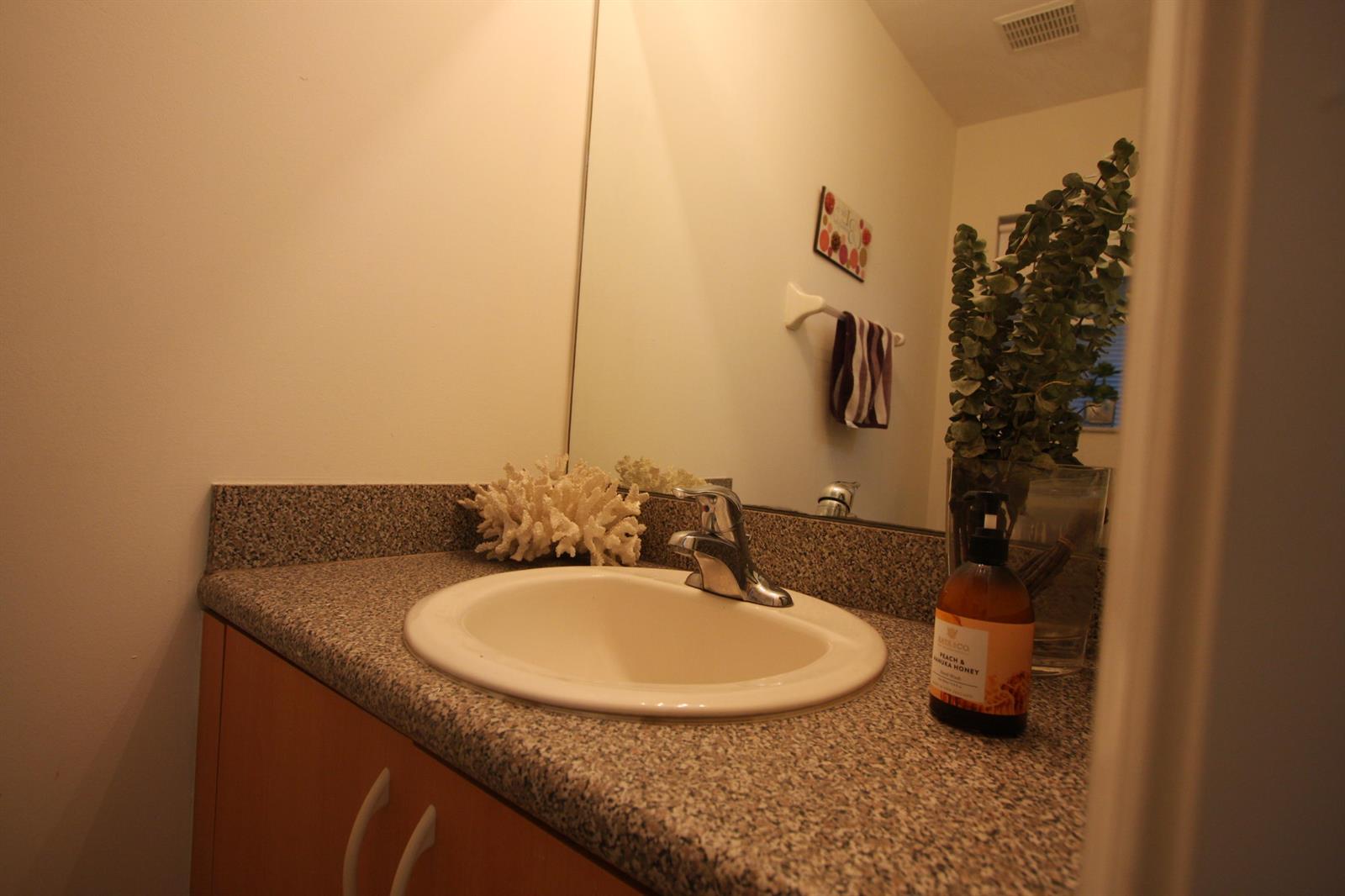 A bathroom vanity features a speckled granite countertop, a white sink, and a wooden cabinet — 945 Imperial Lake Road, FL 33413, FL