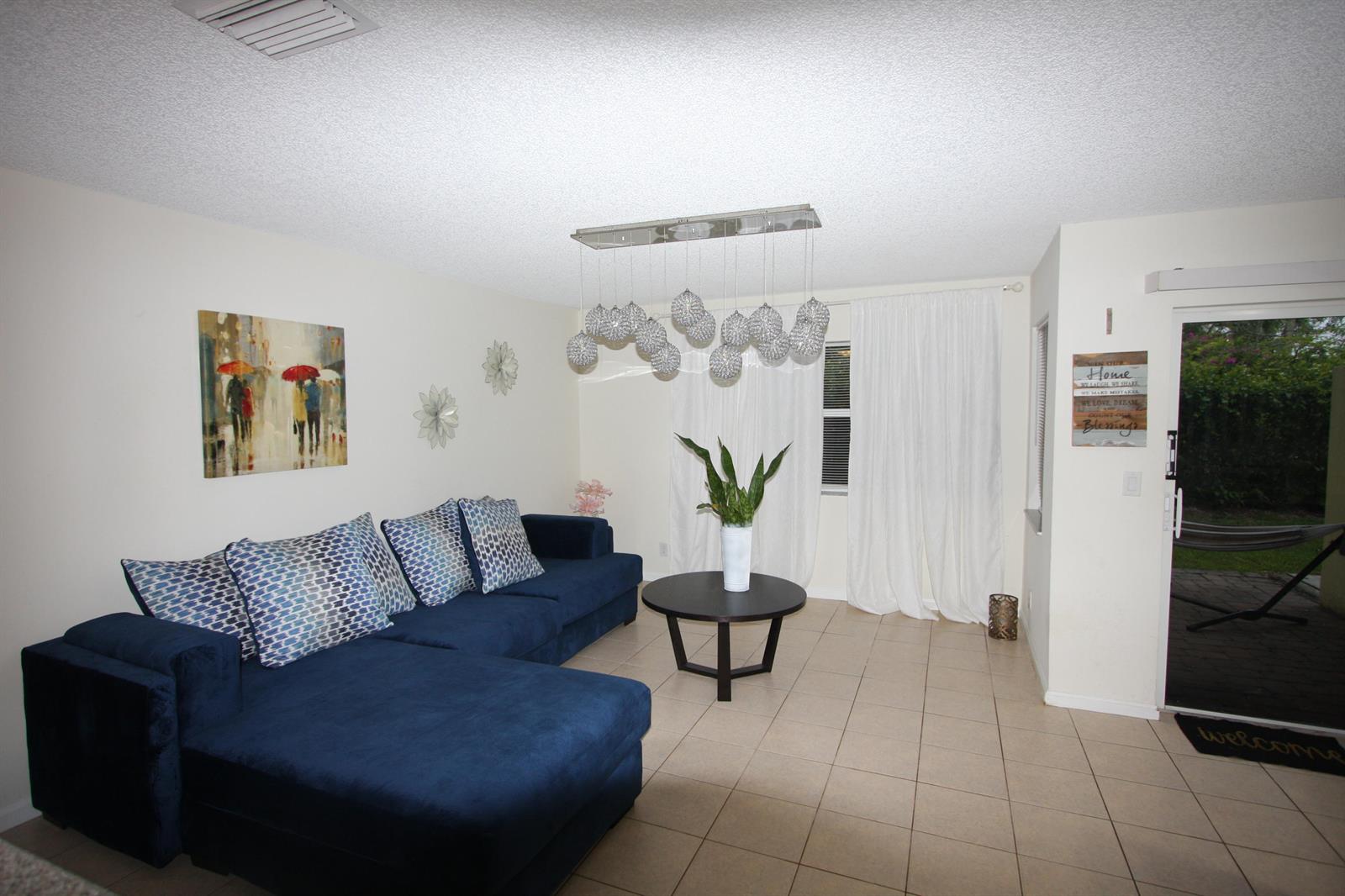 A living room features a blue sectional sofa, a round coffee table, and a chandelier — 945 Imperial Lake Road, FL 33413, FL