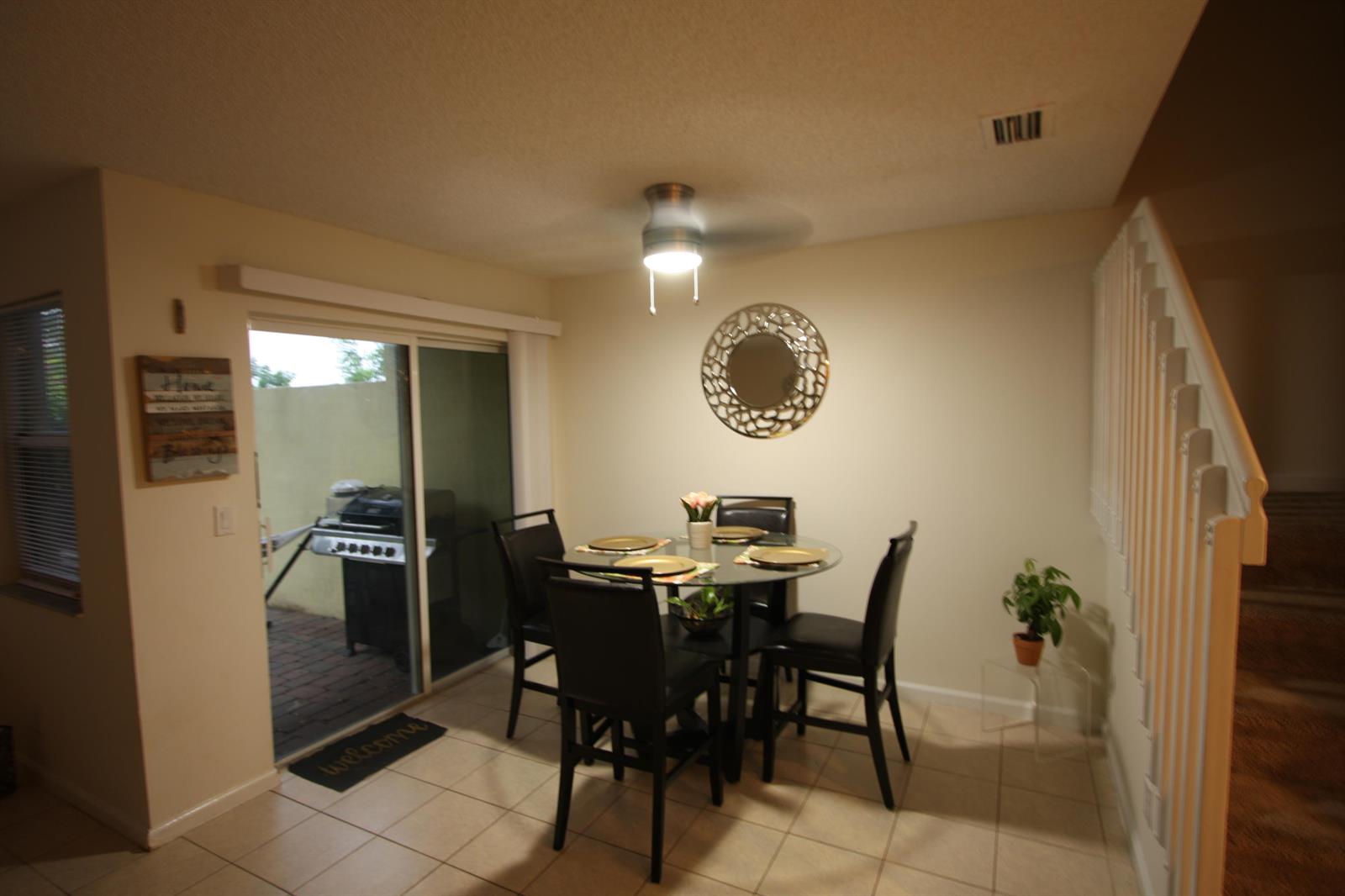 A dining area with a glass table, four chairs, a ceiling fan, and sliding glass doors — 945 Imperial Lake Road, FL 33413, FL
