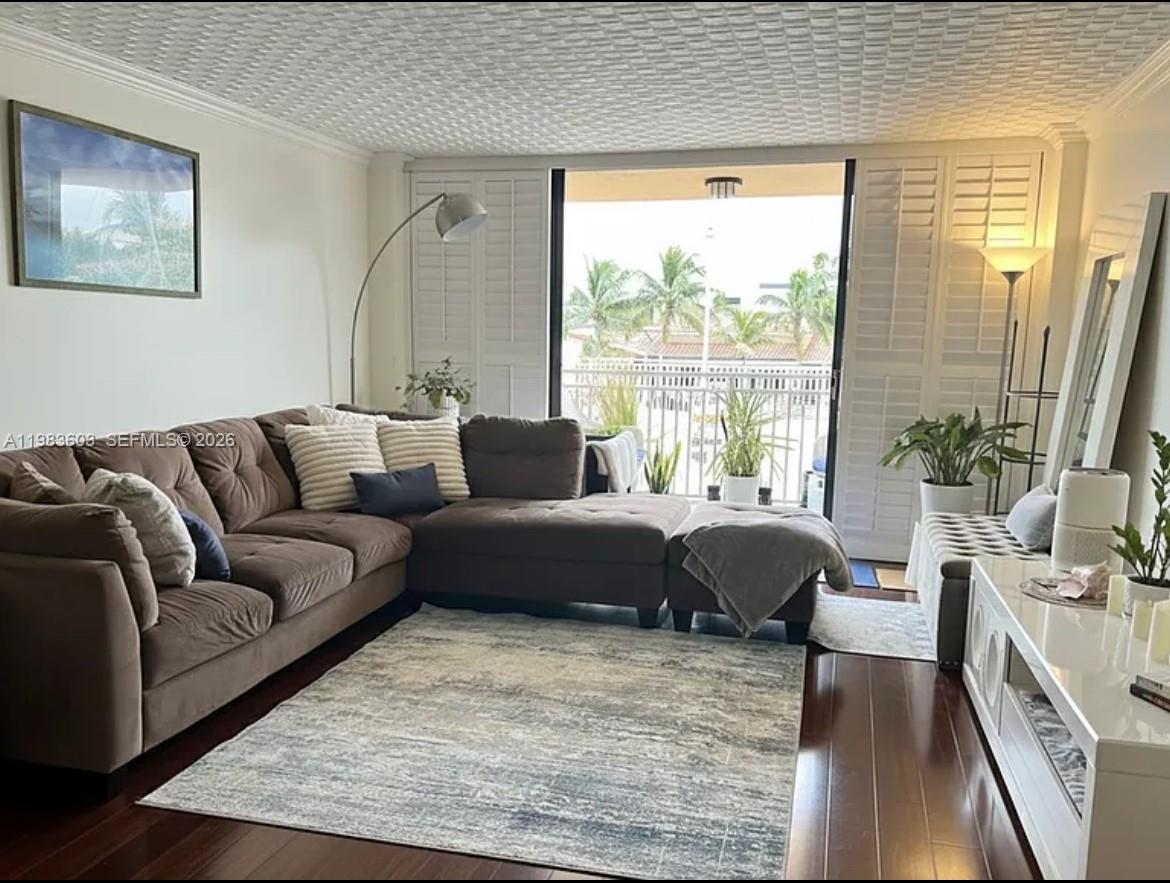 A living room features a brown sectional sofa, a patterned rug, and a balcony view — 2450 NE 135th St # 103, North Miami FL 33181, NORTH MIAMI, FL