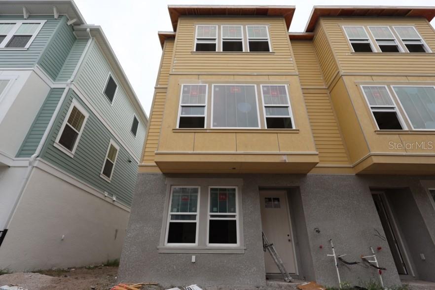 The exterior of a three-story townhouse features yellow siding, a stucco base, and white trim — 458 31ST WAY N, ST PETERSBURG, FL