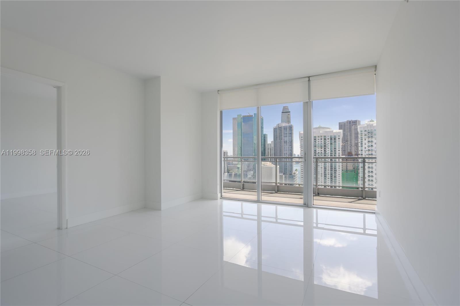 An empty room with white walls, glossy tile floors, and large windows overlooking city buildings — 92 SW 3rd St # 3512, Miami FL 33130, MIAMI, FL
