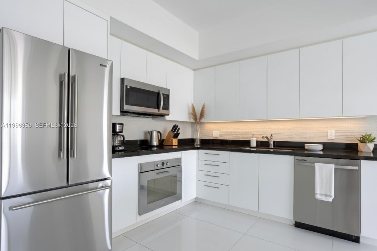 A modern kitchen features white cabinets, stainless steel appliances, and black countertops — 92 SW 3rd St # 3512, Miami FL 33130, MIAMI, FL