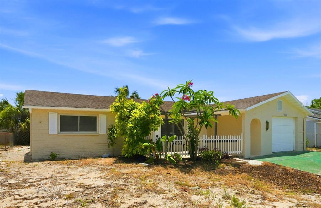 A single-story house with a light yellow exterior, a small front porch, and a garage — 6430 BALDWYN AVENUE, NEW PORT RICHEY, FL