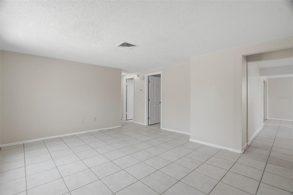An empty room with light-colored tile flooring, beige walls, and a white ceiling — 6430 BALDWYN AVENUE, NEW PORT RICHEY, FL