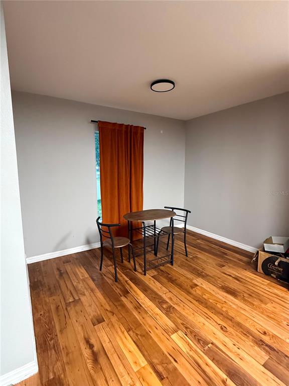 A dining area features hardwood floors, gray walls, a small table with two chairs, and orange curtains — 235 ELEUTHERA DRIVE, LAKE ALFRED, FL