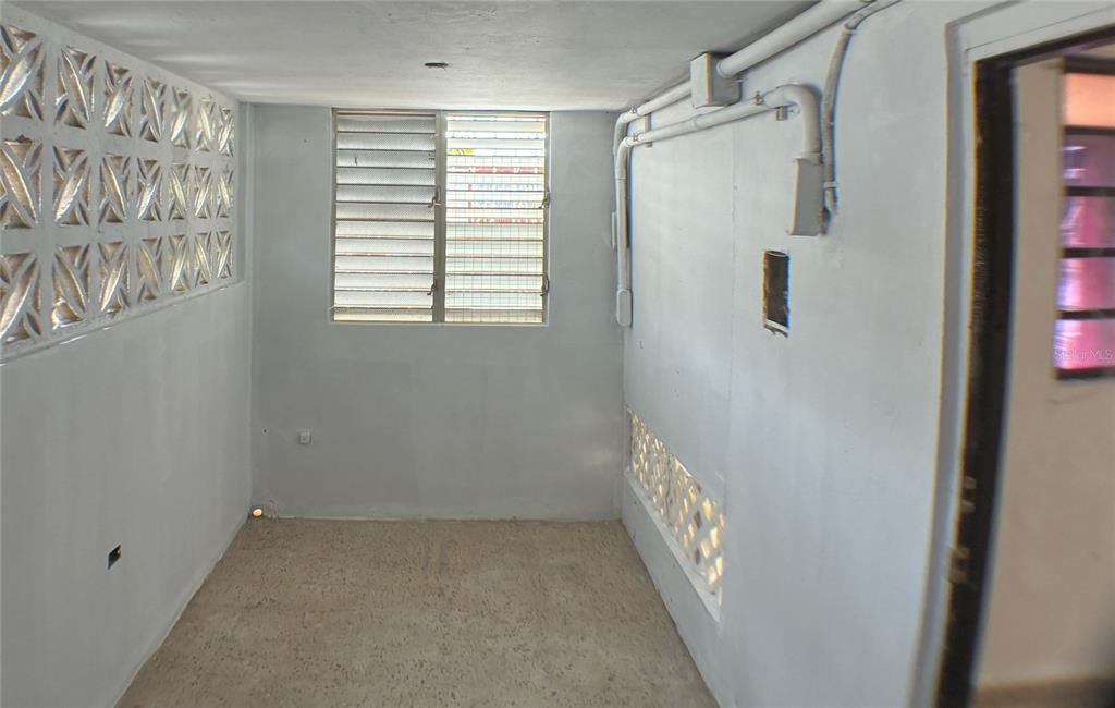 A small, unfinished room features light-colored walls, a louvered window, and decorative breeze block accents — 11 LAS VEGAS DEVELOPMENT UNIT N-1, CATANO, PR