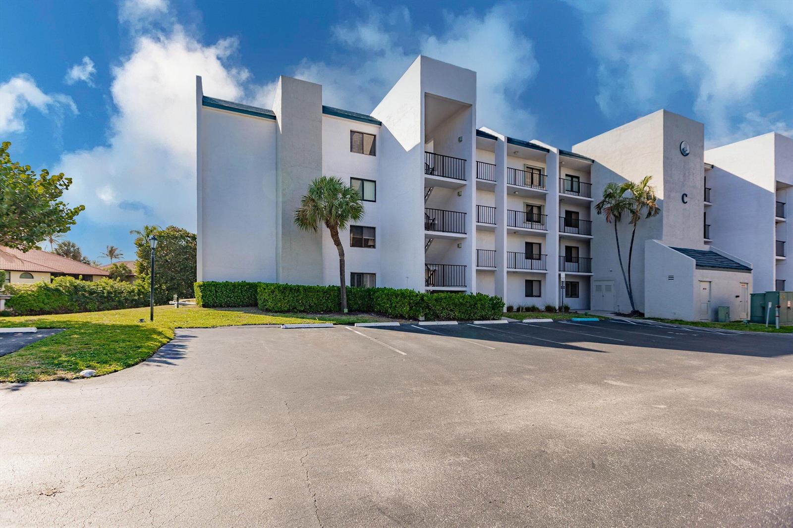 A multi-story white apartment building with balconies and a parking lot in the foreground — 1605 S Us Highway 1 # C104, Jupiter FL 33477, JUPITER, FL