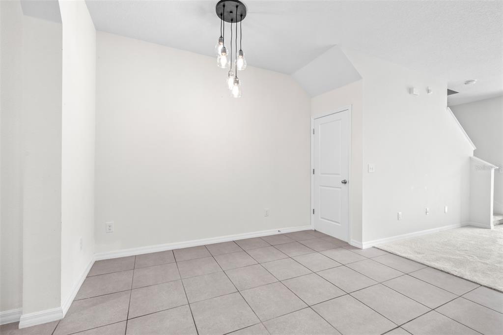 An empty dining area features large square floor tiles, a modern pendant light, and white walls — 32960 KALOKO ROAD, WESLEY CHAPEL, FL