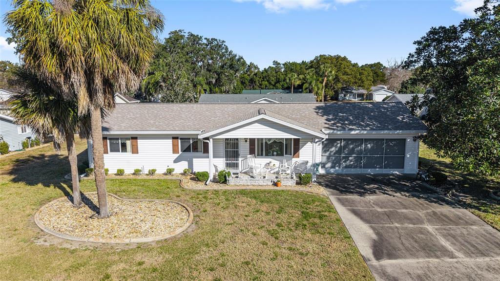 A single-story house with white siding, a gray roof, a front porch, and a driveway — 10319 SE 177TH PLACE, SUMMERFIELD, FL