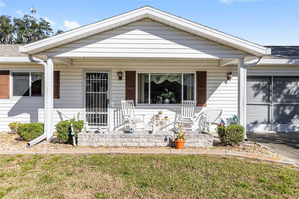 A single-story house with white siding, a covered front porch, and a brick planter — 10319 SE 177TH PLACE, SUMMERFIELD, FL