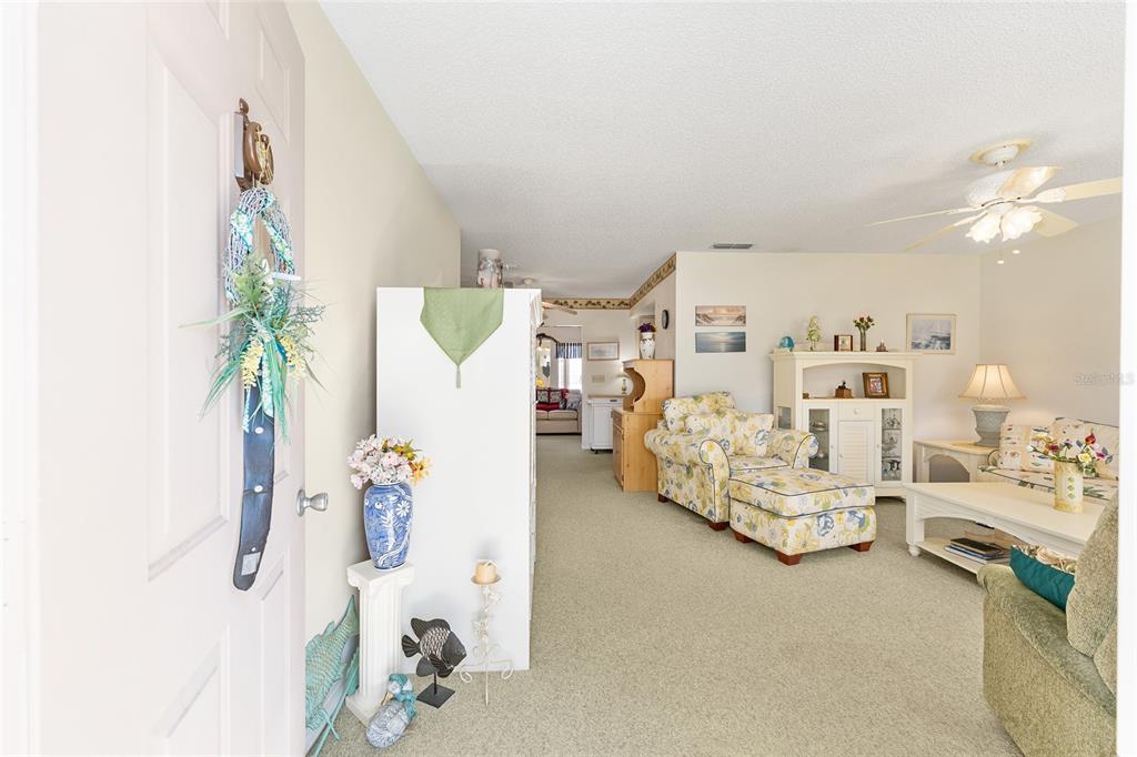 A living room features beige carpeting, floral furniture, a ceiling fan, and a white cabinet — 10319 SE 177TH PLACE, SUMMERFIELD, FL