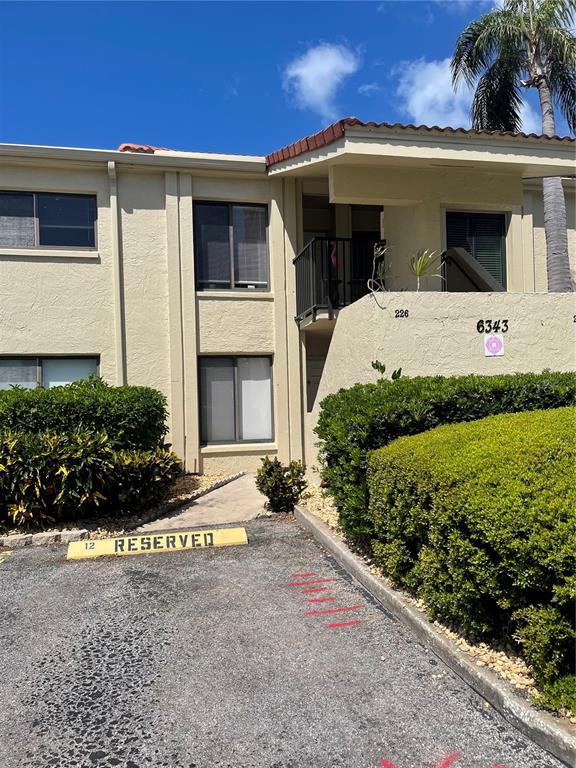 A two-story stucco apartment building features a reserved parking space and a second-floor balcony — 6343 PALMA DEL MAR BOULEVARD S UNIT 226, ST PETERSBURG, FL