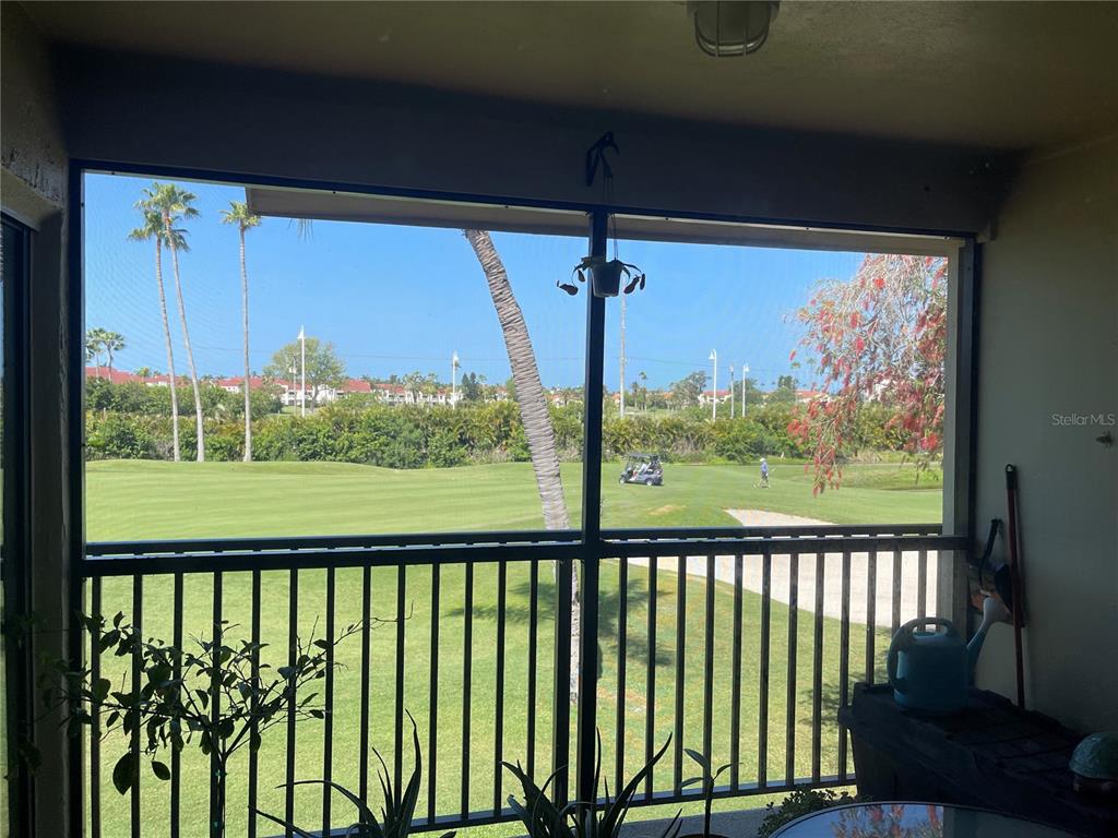 A screened-in balcony overlooks a green golf course with palm trees and distant buildings — 6343 PALMA DEL MAR BOULEVARD S UNIT 226, ST PETERSBURG, FL