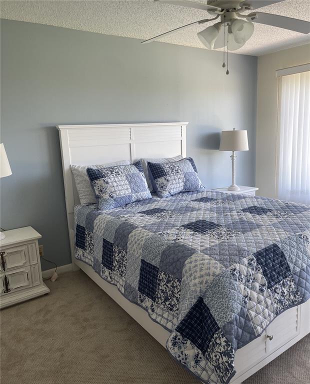 A bedroom features a white bed frame, a blue patchwork quilt, and two matching nightstands — 6343 PALMA DEL MAR BOULEVARD S UNIT 226, ST PETERSBURG, FL