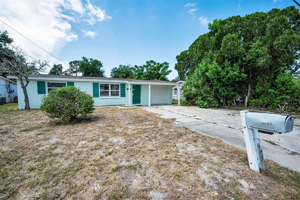 A light green single-story house with a driveway and a mailbox in the front yard — 7402 COUNTRY CLUB DRIVE, HUDSON, FL