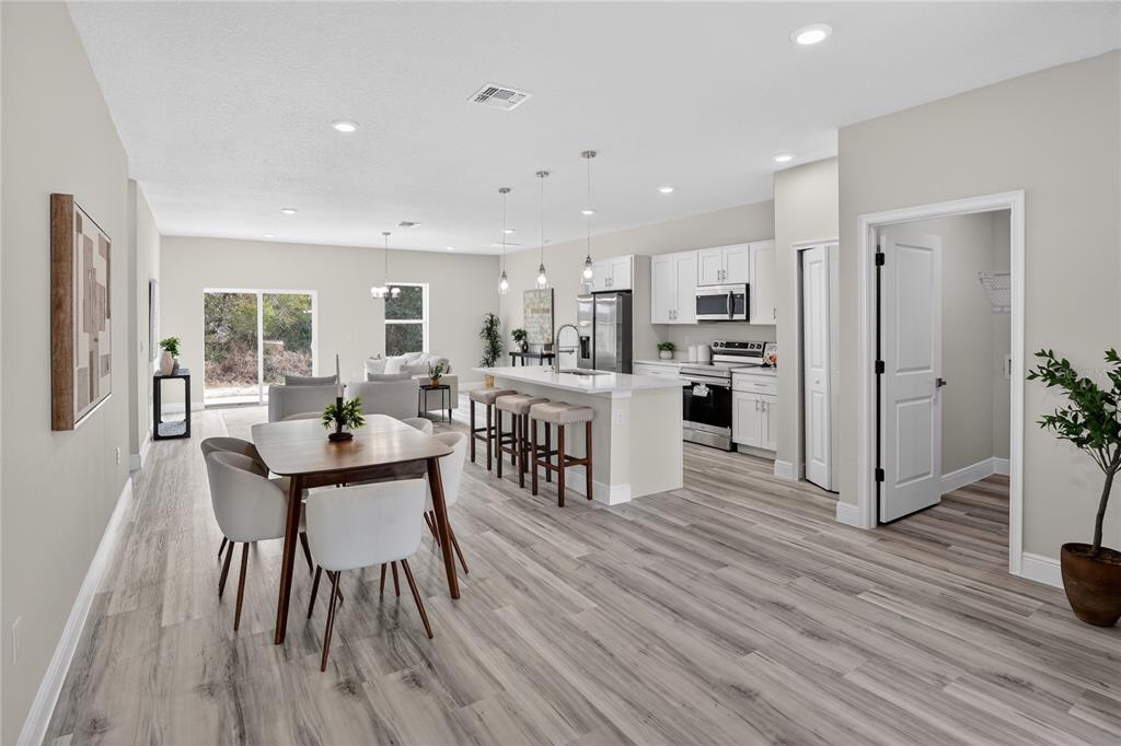 An open-concept kitchen and dining area features light wood-look flooring, white cabinetry, and a kitchen island — 15742 SW 37TH CIRCLE, OCALA, FL