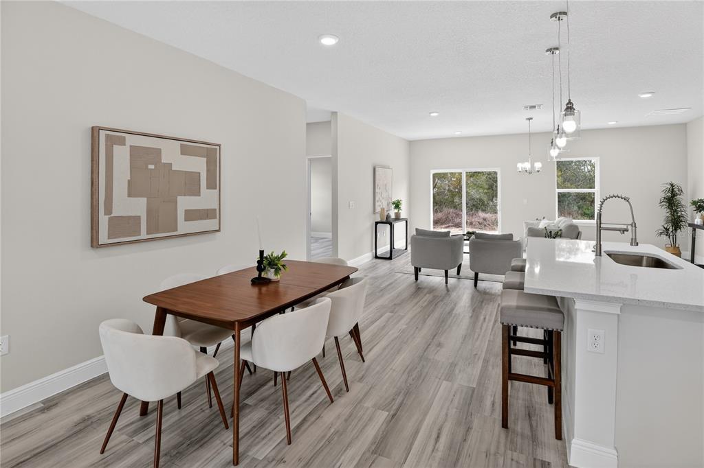 An open-concept dining and kitchen area features light wood-look flooring and modern neutral decor — 15742 SW 37TH CIRCLE, OCALA, FL