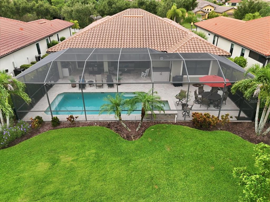 An aerial view of a backyard featuring a screened-in pool, patio, and landscaped lawn — 10120 BELCREST BOULEVARD, FORT MYERS, FL