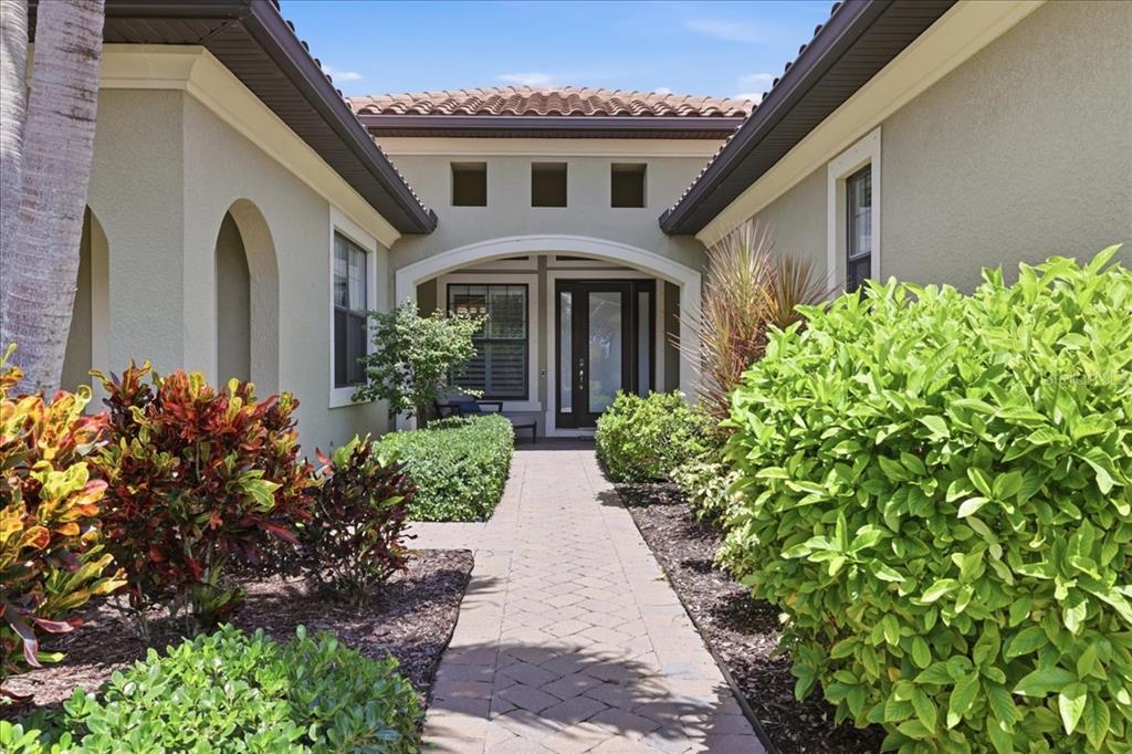 A paved walkway leads to the front entrance of a house with a tiled roof — 10120 BELCREST BOULEVARD, FORT MYERS, FL