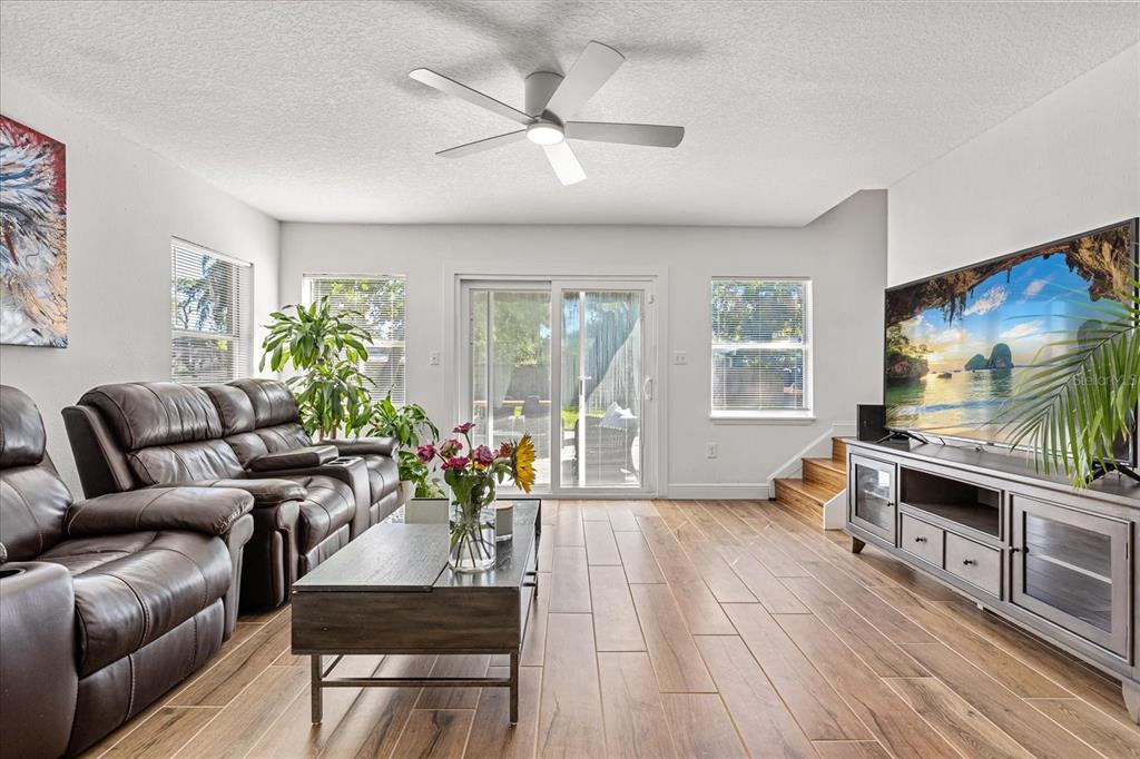 A living room features wood-look tile flooring, a leather sofa, a ceiling fan, and a television — 2418 EUSTON ROAD, WINTER PARK, FL