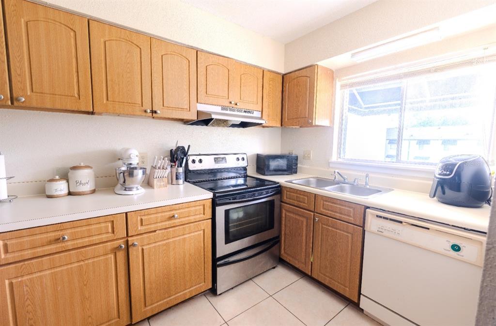 A kitchen features oak cabinets, stainless steel appliances, white countertops, and a double sink — 4267 S SEMORAN BOULEVARD UNIT 11, ORLANDO, FL