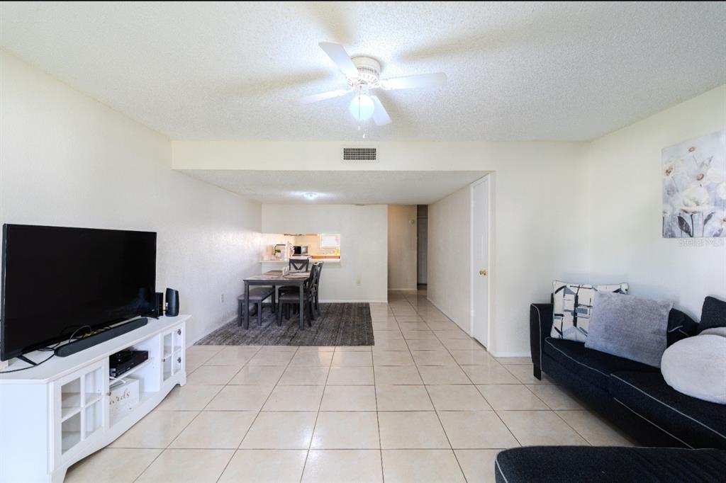 An open-concept living and dining area with white walls, tile flooring, and a ceiling fan — 4267 S SEMORAN BOULEVARD UNIT 11, ORLANDO, FL
