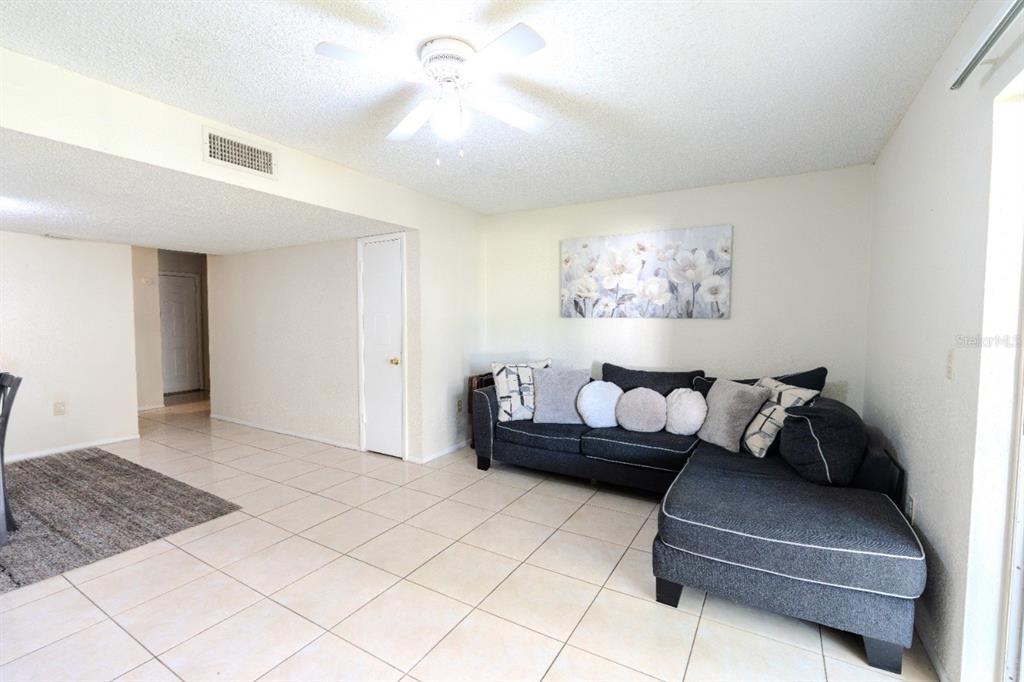 A living room features a dark gray sectional sofa, tile flooring, and a ceiling fan — 4267 S SEMORAN BOULEVARD UNIT 11, ORLANDO, FL