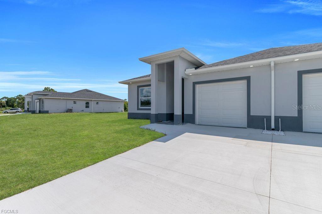 A view of the exterior of a modern house with a garage and lawn — 4648/4650 LEONARD BOULEVARD S, LEHIGH ACRES, FL