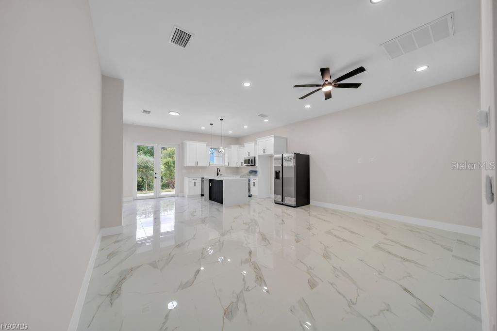 A bright kitchen and living area features white cabinets, a center island, and marble flooring — 4648/4650 LEONARD BOULEVARD S, LEHIGH ACRES, FL