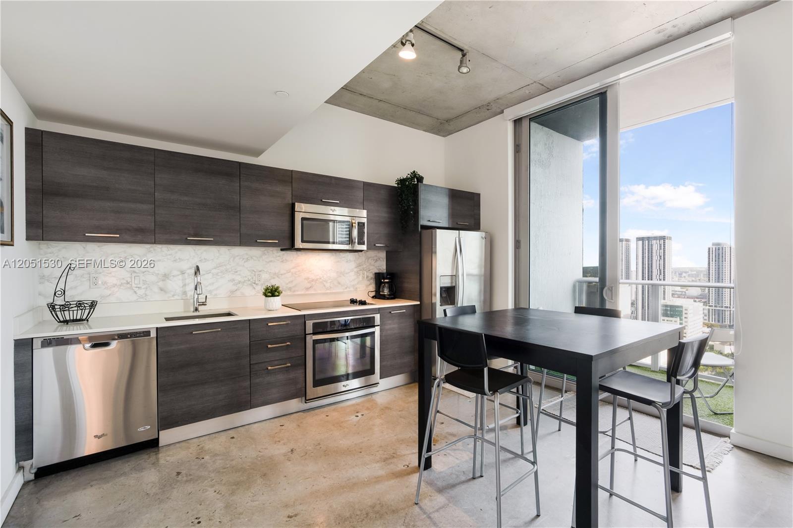 A modern kitchen features dark wood cabinets, stainless steel appliances, and a concrete ceiling — 151 SE 1st St # 3408, Miami FL 33131, MIAMI, FL