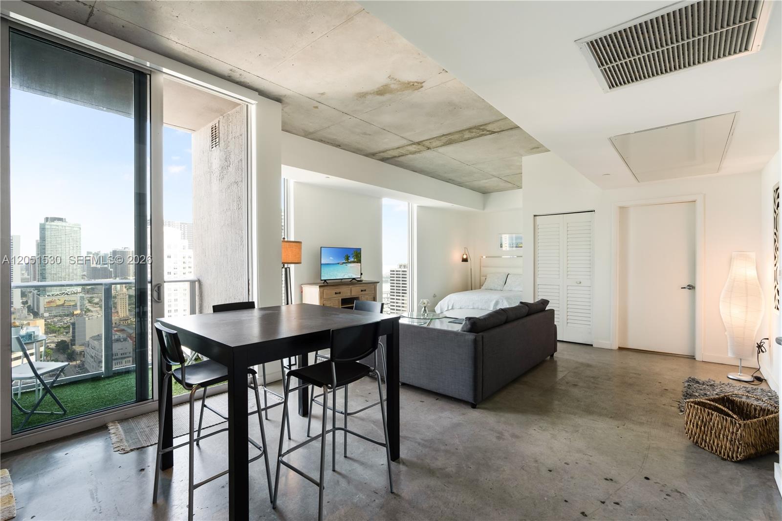 A studio apartment features a concrete ceiling, polished concrete floors, and a balcony with city views — 151 SE 1st St # 3408, Miami FL 33131, MIAMI, FL