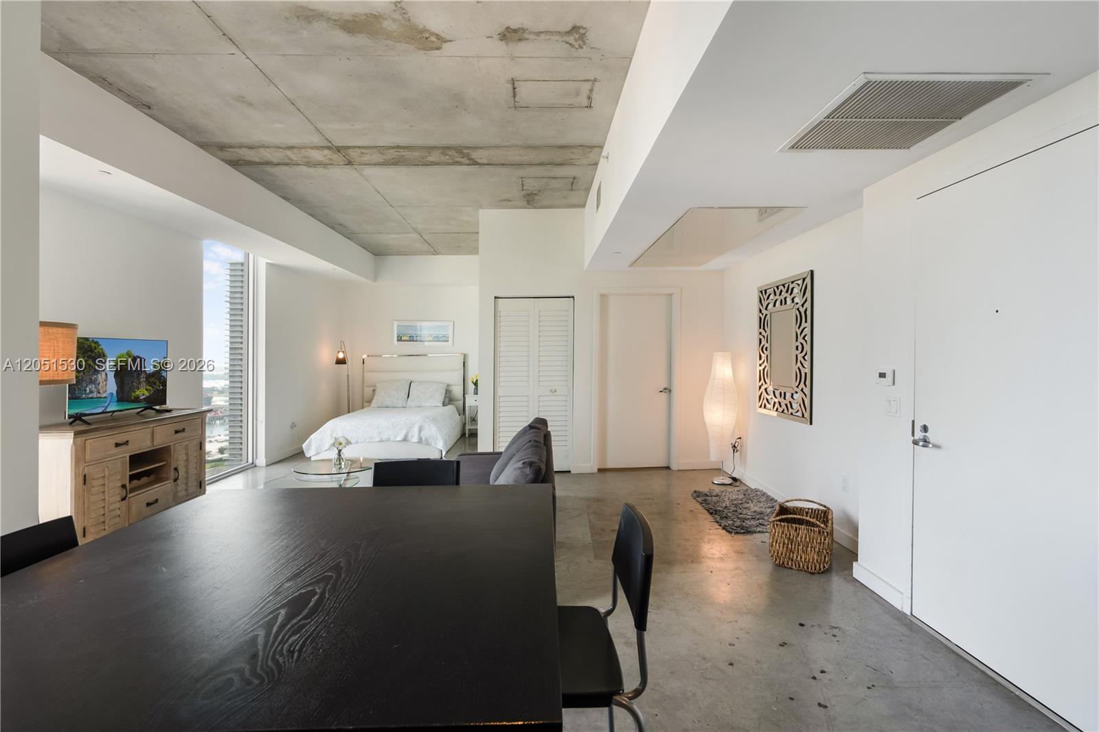 A studio apartment features a concrete ceiling, polished concrete floors, and a view of skyscrapers — 151 SE 1st St # 3408, Miami FL 33131, MIAMI, FL