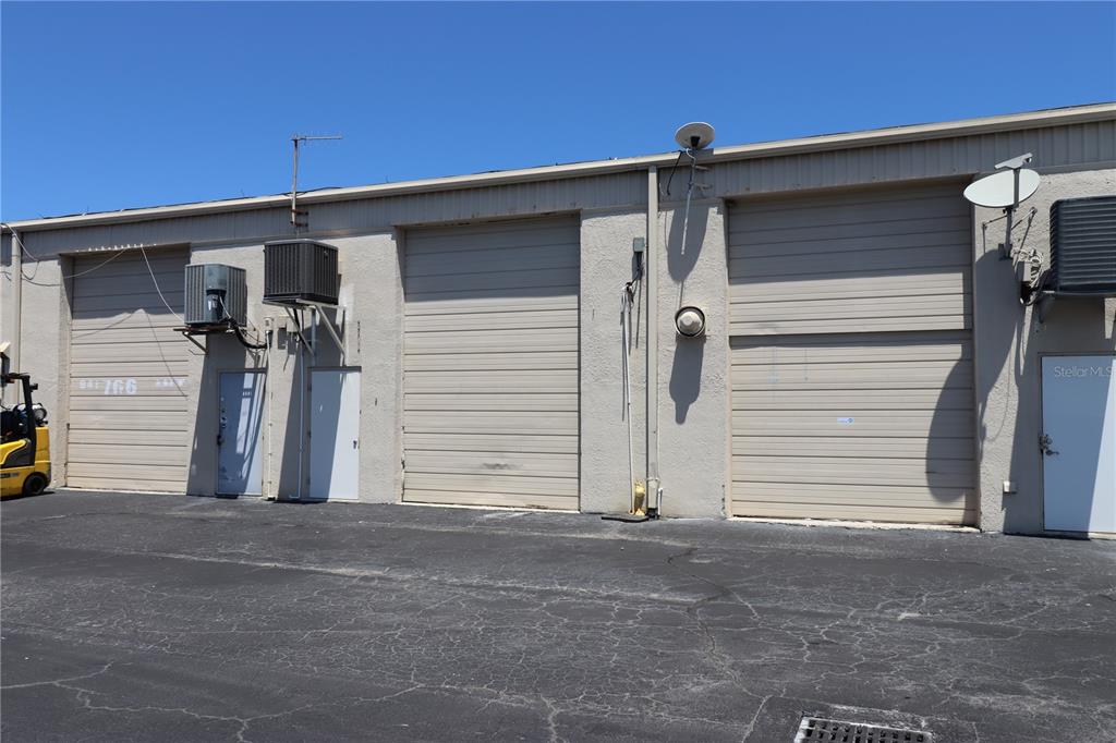 An exterior view of a commercial building with three roll-up doors and two entry doors — 1225 TAMIAMI TRAIL UNIT A7, PORT CHARLOTTE, FL