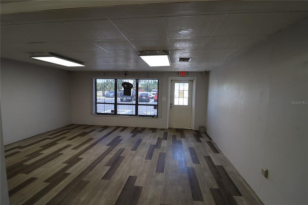 An empty commercial room features wood-look vinyl flooring, a drop ceiling, and a large window — 1225 TAMIAMI TRAIL UNIT A7, PORT CHARLOTTE, FL