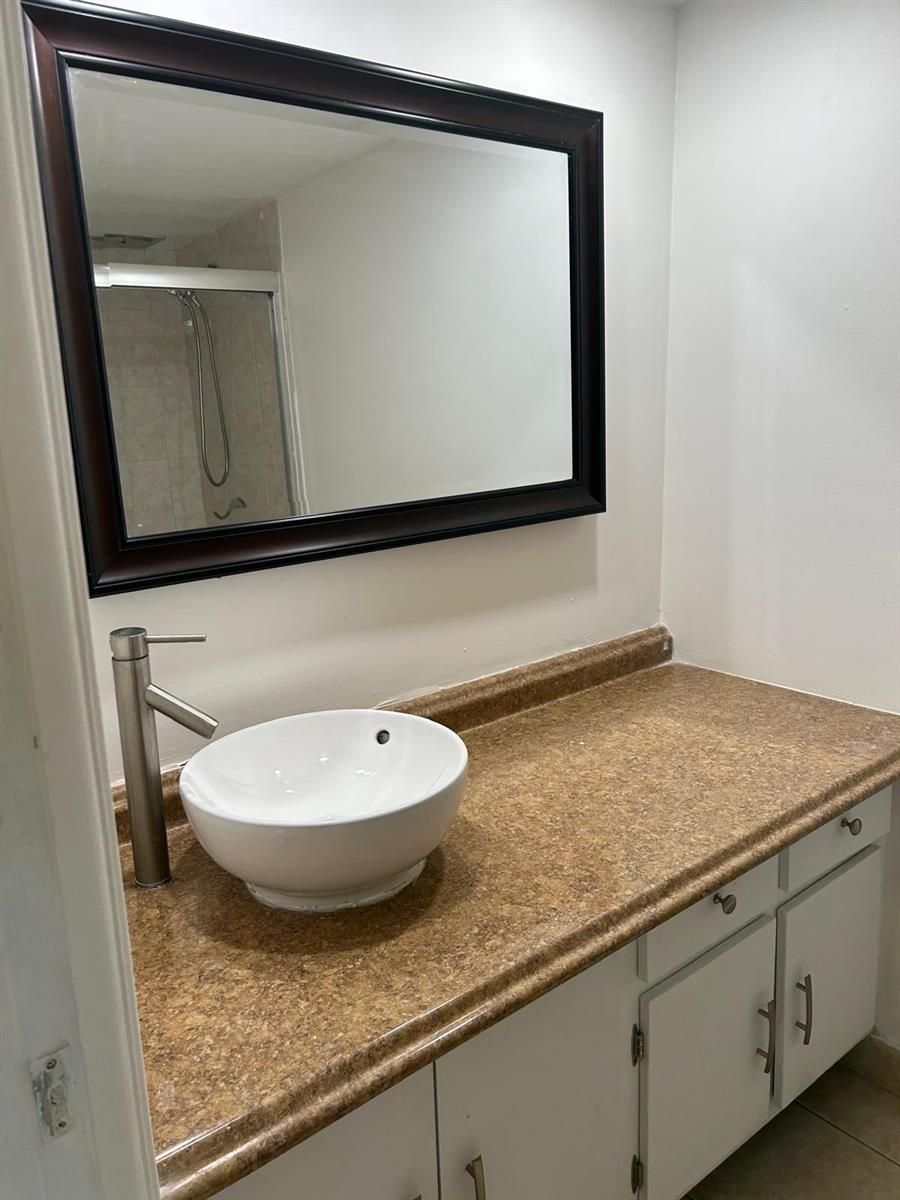 A bathroom vanity features a white vessel sink, a tall faucet, and a dark-framed mirror — 2661 S Course Drive # 703, Pompano Beach FL 33069, POMPANO BEACH, FL
