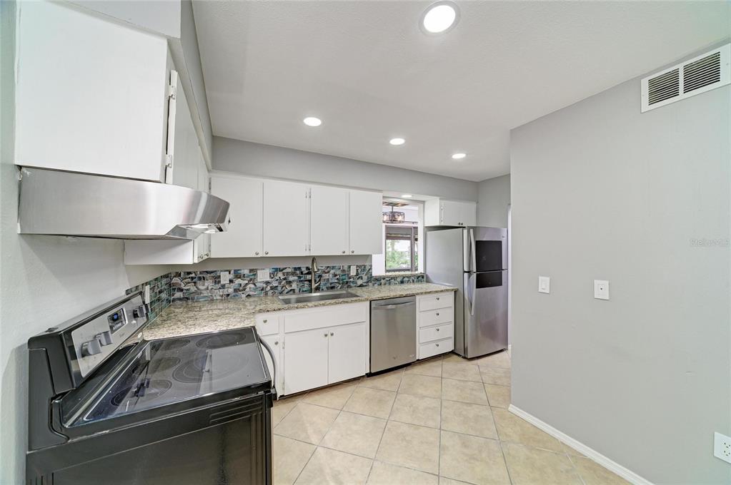A kitchen features white cabinets, granite countertops, stainless steel appliances, and a tiled floor — 2224 BAHIA VISTA STREET UNIT E6, SARASOTA, FL