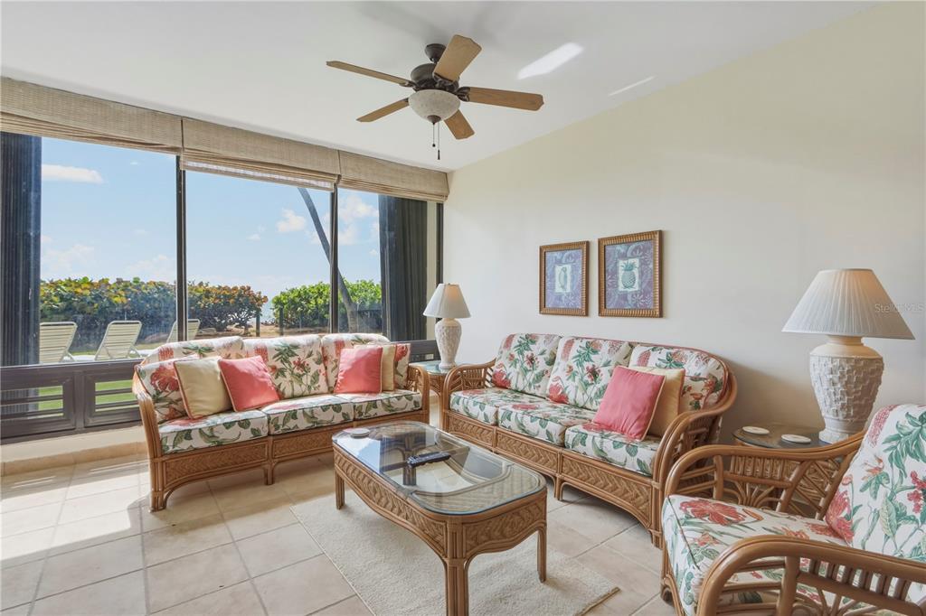 A living room features rattan furniture, floral cushions, a glass coffee table, and large windows — 96 BEACH VILLAGE DRIVE UNIT 96, HUMACAO, PR